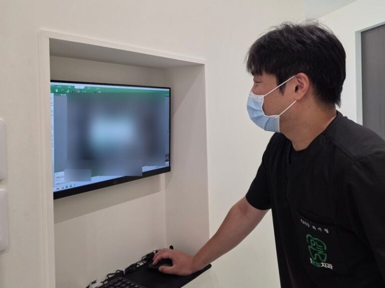 마스크 쓴 의사가 모니터를 보며 마우스를 조작하고 있다.
