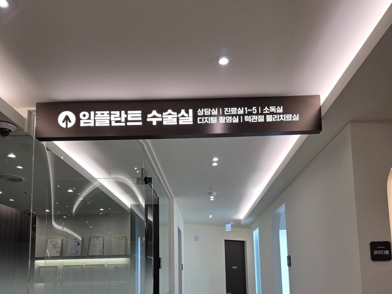 하양주변치과 잇몸에서 피가 나는 이유와 관리법 9 치과 내부 복도에 '임플란트 수술실'을 안내하는 표지판