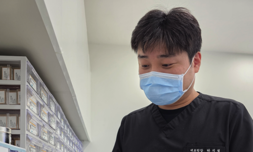 마스크를 쓴 치과 의사가 차트를 보고 있다.